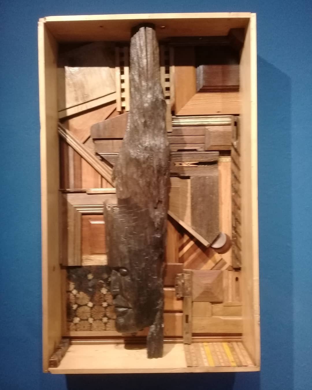 Caixa 06, a wooden relief with a carved vertical element set against assembled wood blocks inside a shallow box.