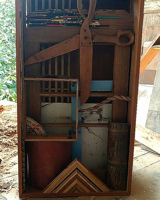 The work Caixa (estudo) combines panels, compartments, and carved wooden shears set inside an open wooden case.