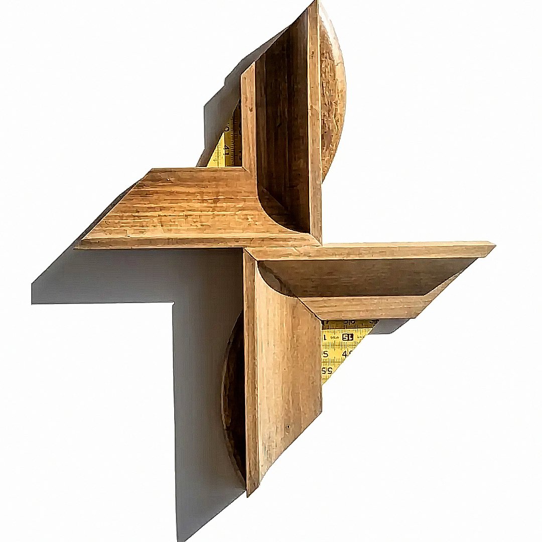 The wall work caixa DNA in wood with angled forms, curved cuts and yellow measuring tape fragments.