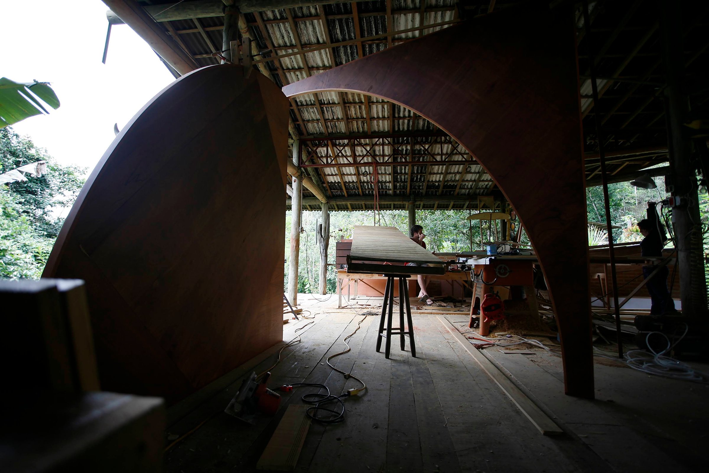 The mobile sculpture Duo in cedar marine plywood and muiracatiara stands in an open workshop with two figures in the background.