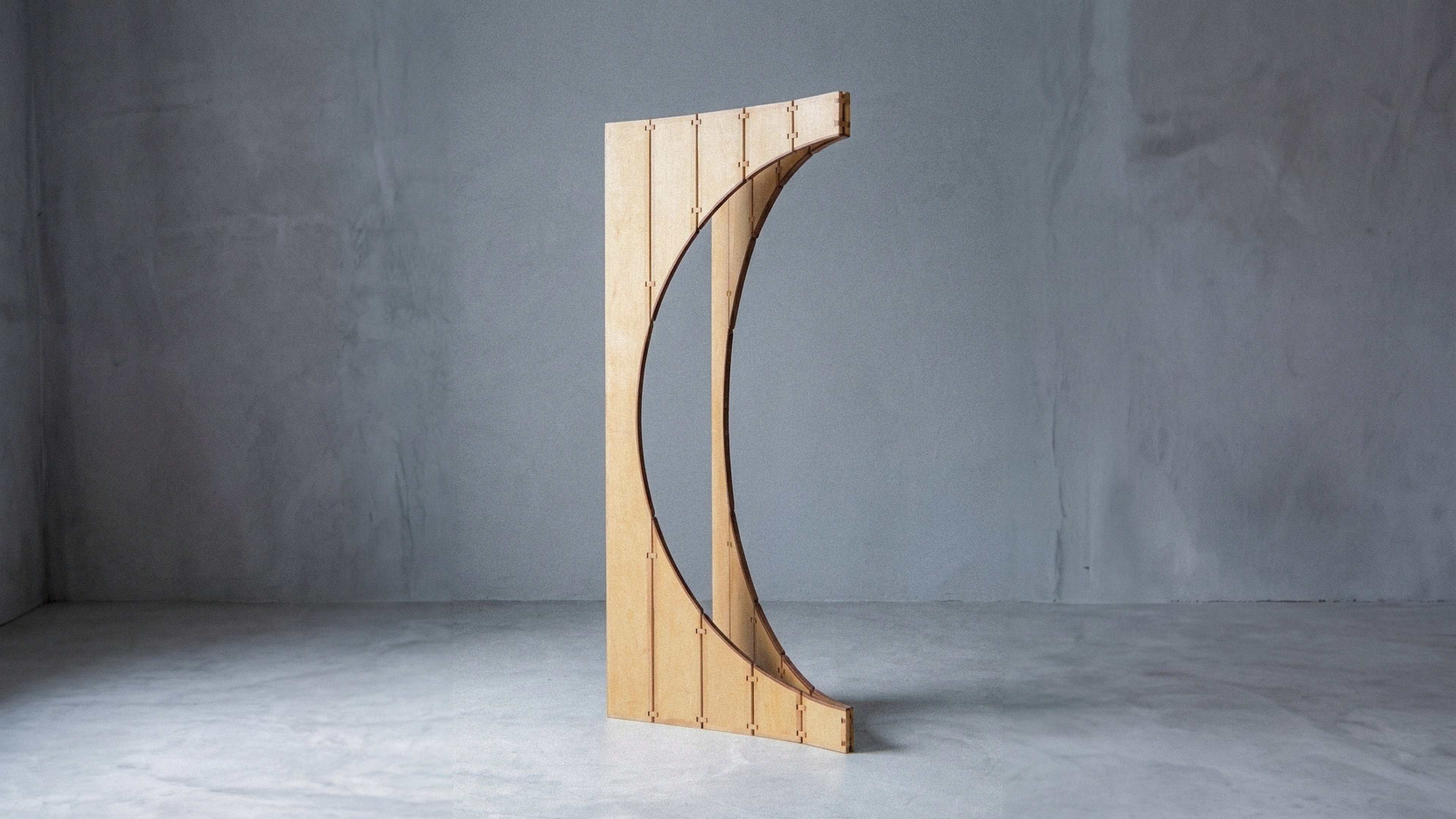 Closer view of the mobile sculpture Ó positioned as a slender crescent form in light wood.