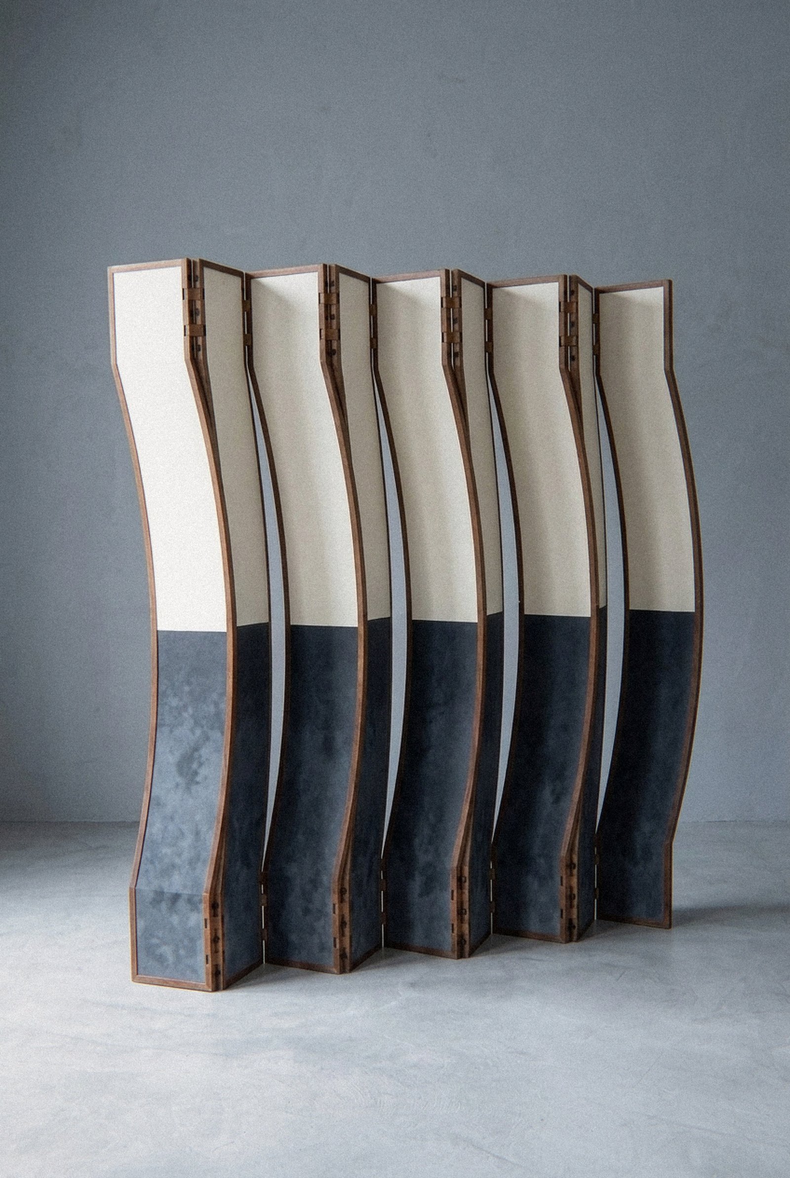 The mobile sculpture Fêmea stands in a zigzag arrangement on a grey floor before a plain wall.