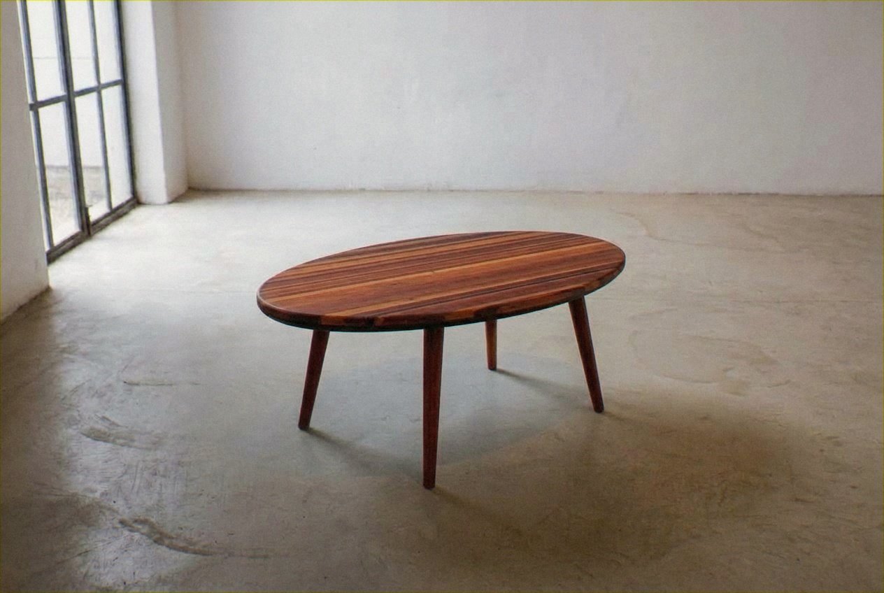 Mesa Ovo in reclaimed wood seen from above on a smooth concrete floor near a tall grid window.