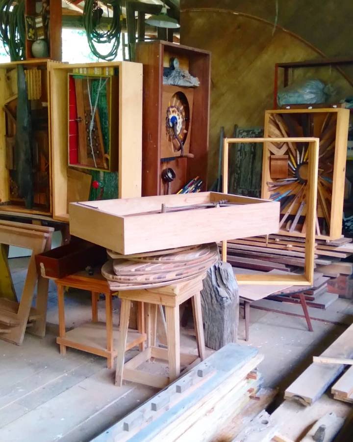 Wooden boxes on trestles and stands surrounded by wooden reliefs and timber inside the workshop.