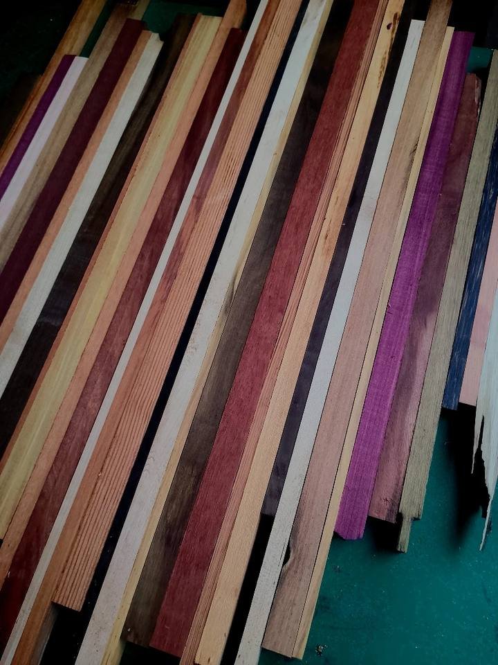 Row of long wooden strips in various tones and natural colors leaning side by side.