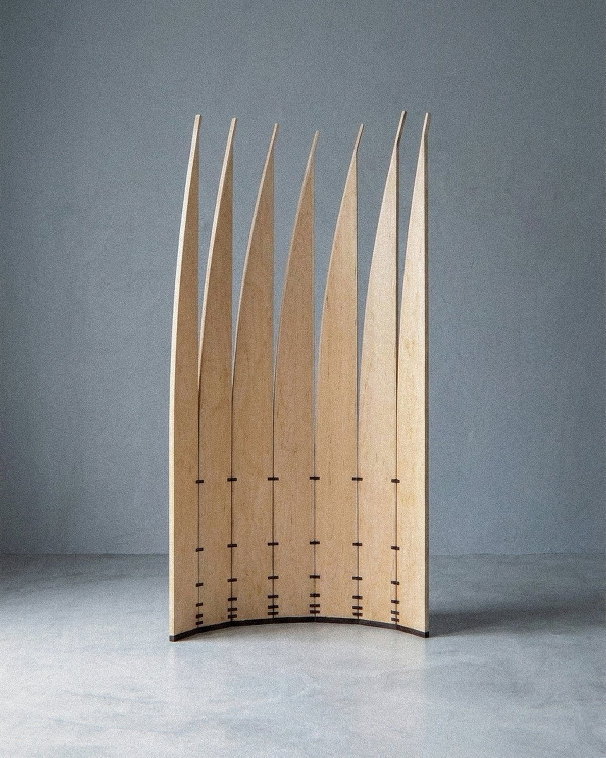 The mobile sculpture Velas standing complete at a distance, arranged in an open curved arc on a grey floor.