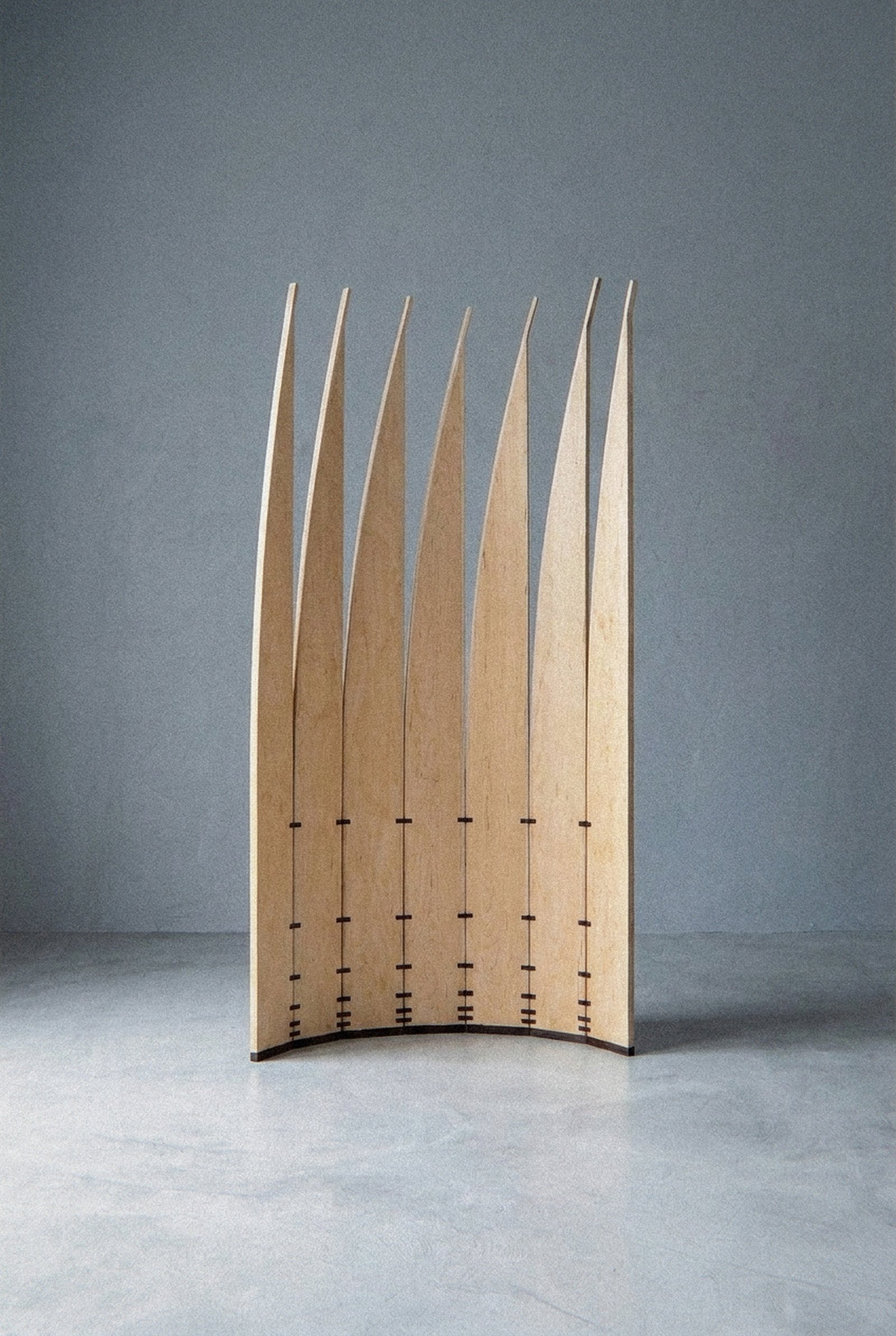The mobile sculpture Velas standing complete at a distance, arranged in an open curved arc on a grey floor.