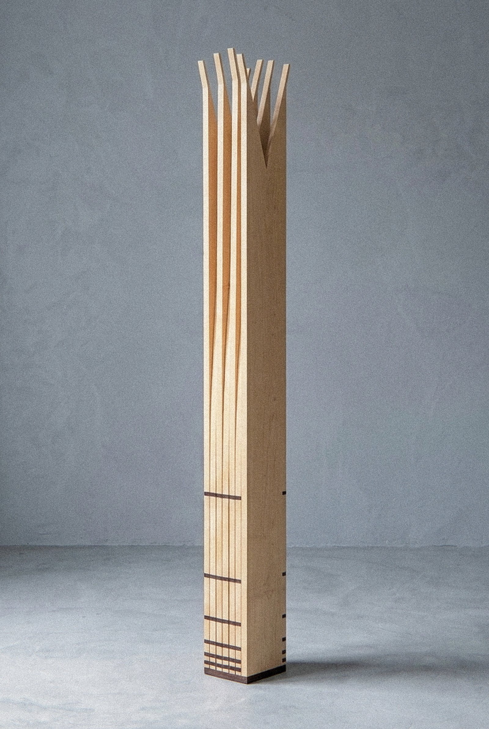 The mobile sculpture Velas seen closer, closed into a vertical column with dark joint marks near the base.