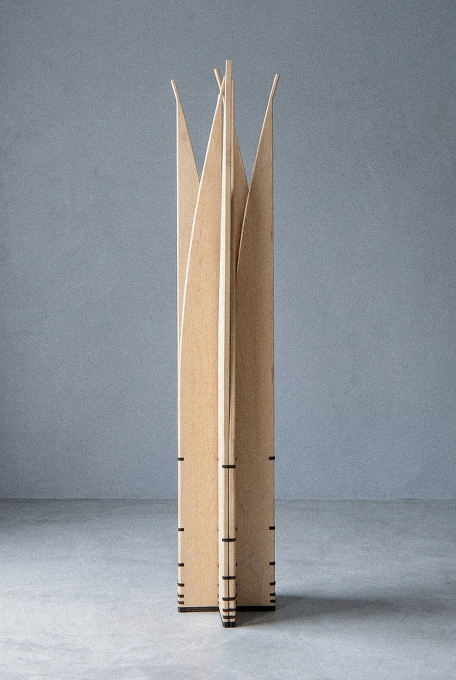 The mobile sculpture Velas seen closer, arranged in a radial star column showing the dark joints along the base.