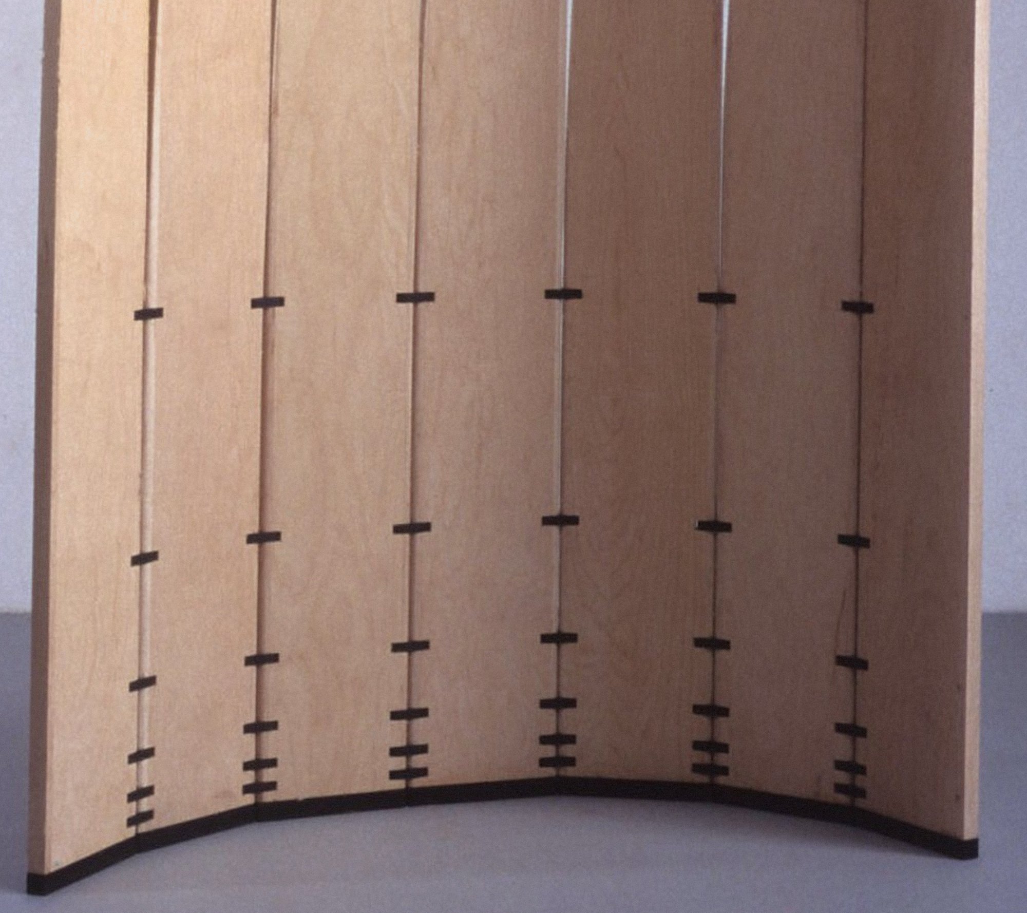 Detail of the lower part of Velas in an arc, showing light wood surfaces and aligned dark joints.